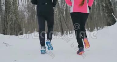 两个跑步者穿着运动鞋在公园冬天跑步的脚的特写。 已婚夫妇参加体育活动